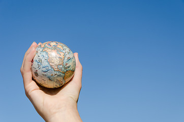 Image showing global earth toy in hand on blue sky background  