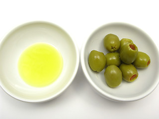 Image showing Two bowls of chinaware with olive oil and olives on white background