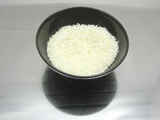Image showing Black bowl of chinaware with coconut flakes on reflecting surface