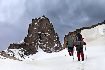 Image showing Two hikers in snowy mountains and storm sky