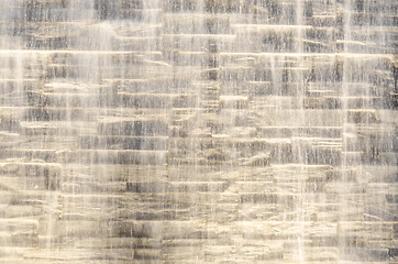 Image showing Falling water stream against stone wall