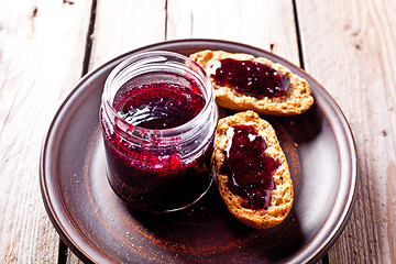 Image showing black currant jam in glass jar and crackers 