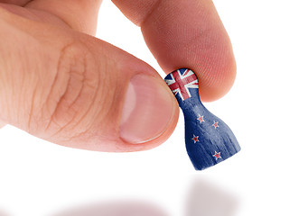 Image showing Hand holding wooden pawn, flag painting, selective focus