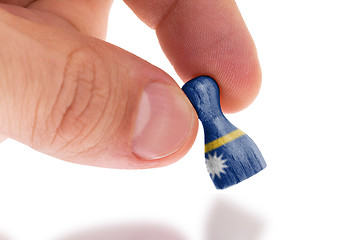Image showing Hand holding wooden pawn, flag painting, selective focus