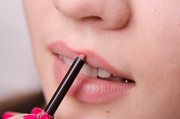 Image showing Makeup artist brings lip pencil beautiful girl