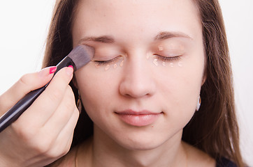 Image showing Makeup artist is shaded brush concealer on eyelids model