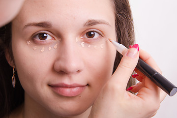 Image showing Makeup artist applies foundation on eyelids of young girl