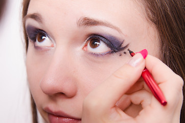 Image showing Makeup artist paints a model's eyes