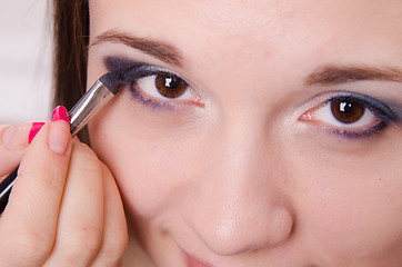 Image showing Makeup artist paints eyelids shadows