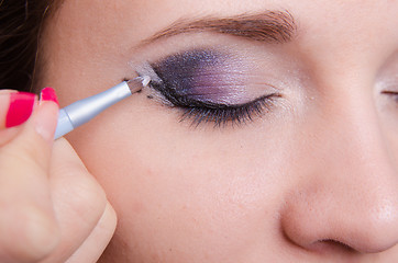 Image showing Makeup artist draws arrows on the right eye girl