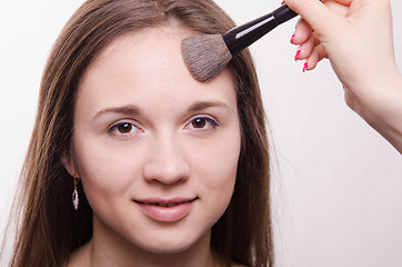 Image showing Makeup artist applies powder on face of a beautiful girl