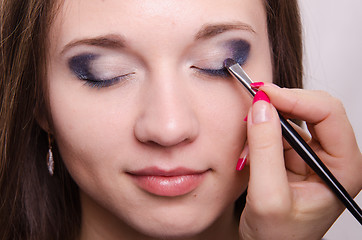 Image showing Drawing bright shadows on girl's eyelids with makeup