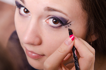 Image showing Makeup artist paints a point over arrows in girl's eyes