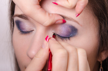 Image showing Makeup artist brings pencil eyelashes girl