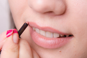 Image showing Makeup artist paints a lip pencil woman