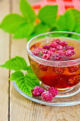 Image showing Tea with raspberries in glass cup and napkin on board