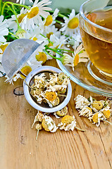 Image showing Herbal chamomile tea with strainer on board