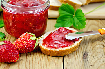 Image showing Bread with strawberry jam and a knife on board