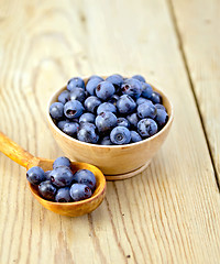 Image showing Blueberries in wooden bowl and spoon on board
