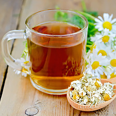 Image showing Herbal chamomile tea in glass mug on board