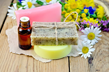 Image showing Soap with oil and wildflowers on board