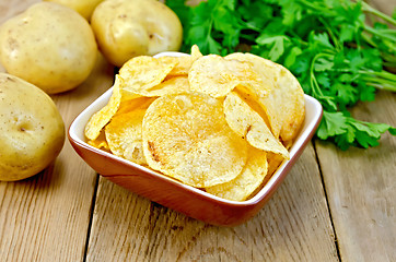 Image showing Chips in clay bowl with potatoes on board