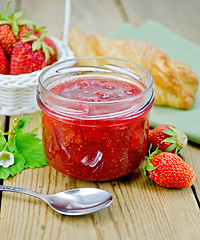 Image showing Jam of strawberry with bun and spoon on board