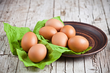 Image showing  fresh brown eggs in plate and green napkin