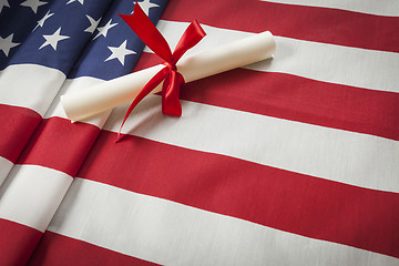 Image showing Ribbon Wrapped Diploma Resting on American Flag with Copy Space