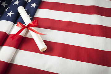 Image showing Ribbon Wrapped Diploma Resting on American Flag with Copy Space