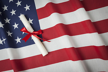 Image showing Ribbon Wrapped Diploma Resting on American Flag with Copy Space