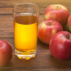 Image showing Glass of apple juice and red apples on wood