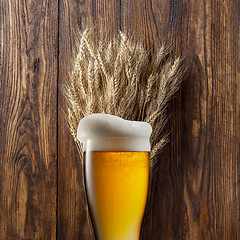 Image showing Glass of beer with wheat on wood