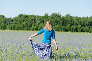 Image showing girl with blue skirt dance in cornflower meadow  