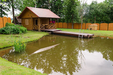 Image showing new rural bathhouse and pond with plank footbridge 