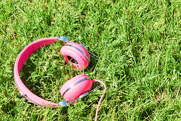Image showing Vivid colorful pink headphones on summer glade