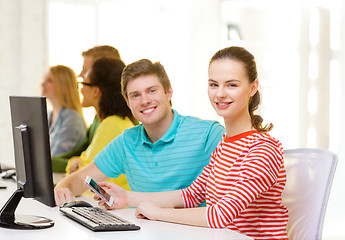 Image showing smiling student with smartphone in computer class