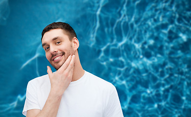 Image showing beautiful smiling man touching his face