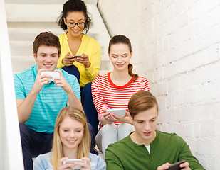 Image showing smiling students with smartphone texting at school