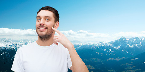 Image showing smiling young handsome man pointing to cheek