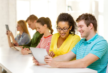 Image showing smiling students looking at tablet pc at school