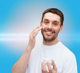 Image showing beautiful smiling man applyin cream