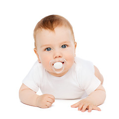 Image showing smiling baby lying on floor with dummy in mouth