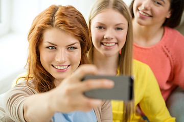 Image showing smiling teenage girls with smartphone at home