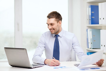 Image showing smiling businessman with laptop and documents
