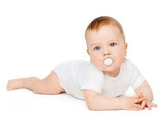 Image showing smiling baby lying on floor with dummy in mouth