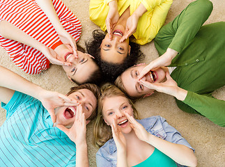 Image showing smiling people lying down on floor and screaming