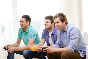 Image showing smiling friends playing video games at home