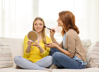 Image showing two smiling teenage girls applying make up at home