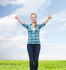 Image showing smiling girl in casual clothes showing thumbs up